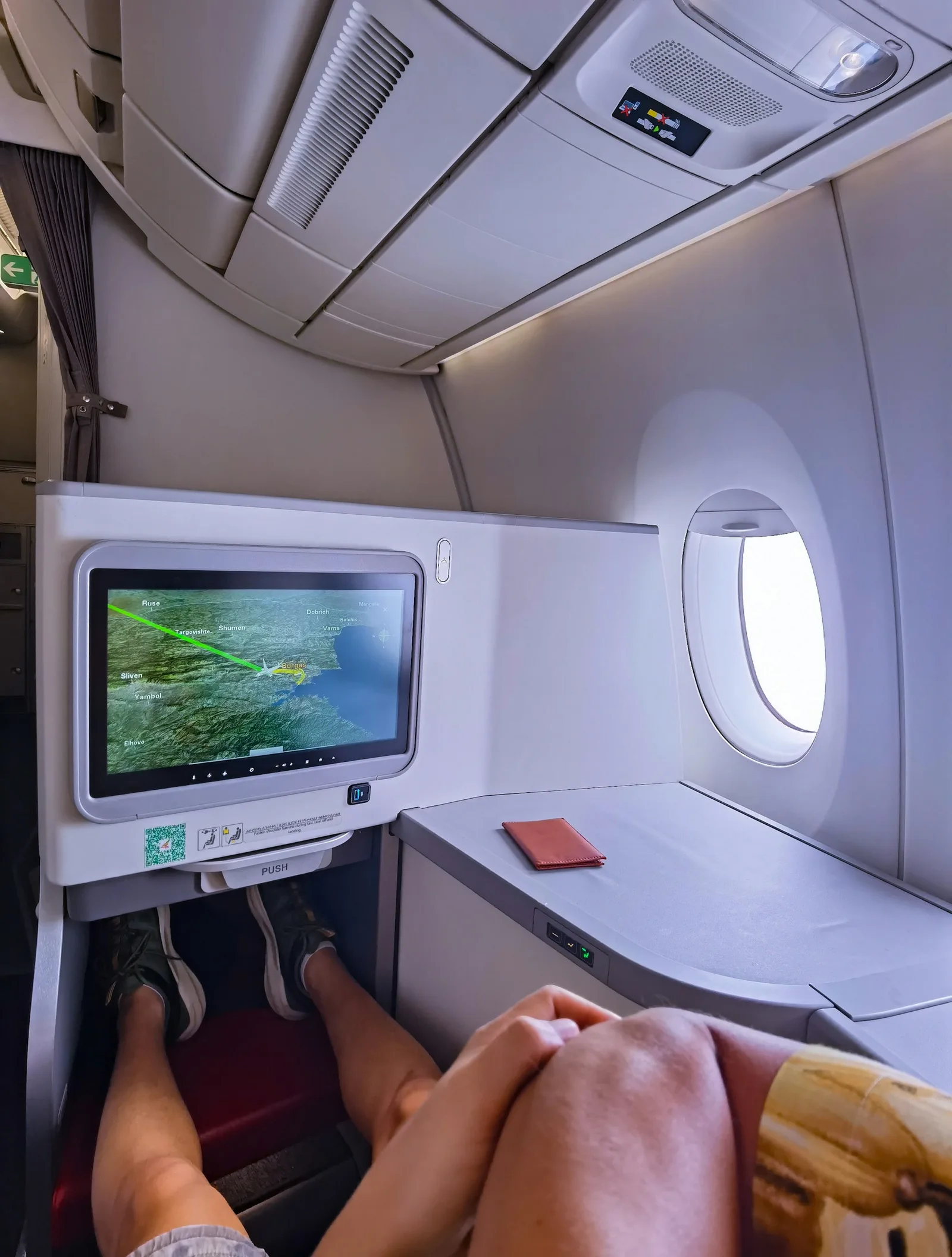 A passenger's legs and feet stretched out in an airplane cabin beside the window