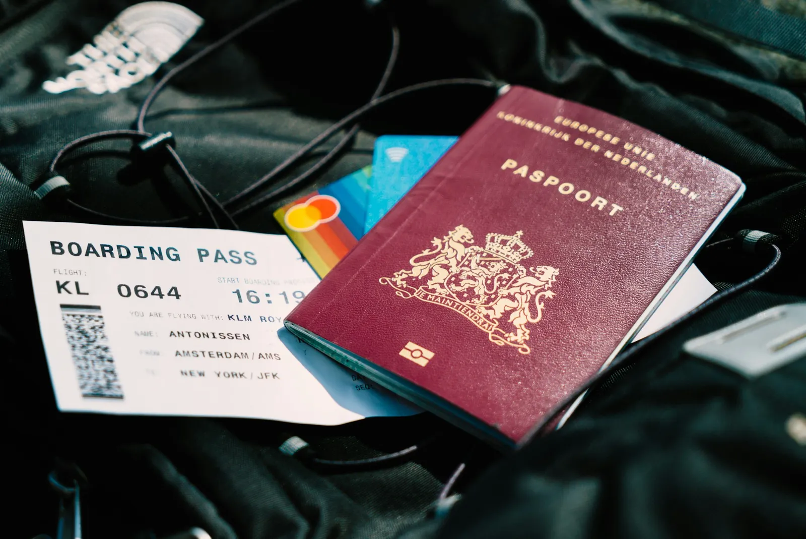 A passport, boarding pass, and contactless cards resting on a black travel bag