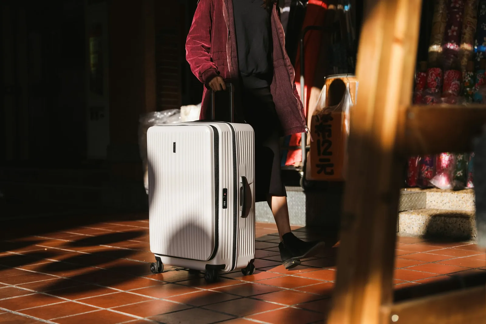 A traveler walking through an airport wheeling a hardside carry-on suitcase
