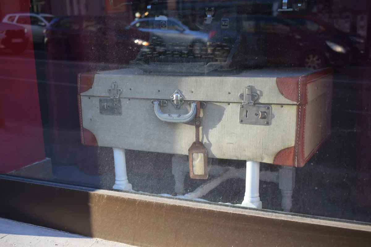 A vintage suitcase with a leather luggage tag attached, on display