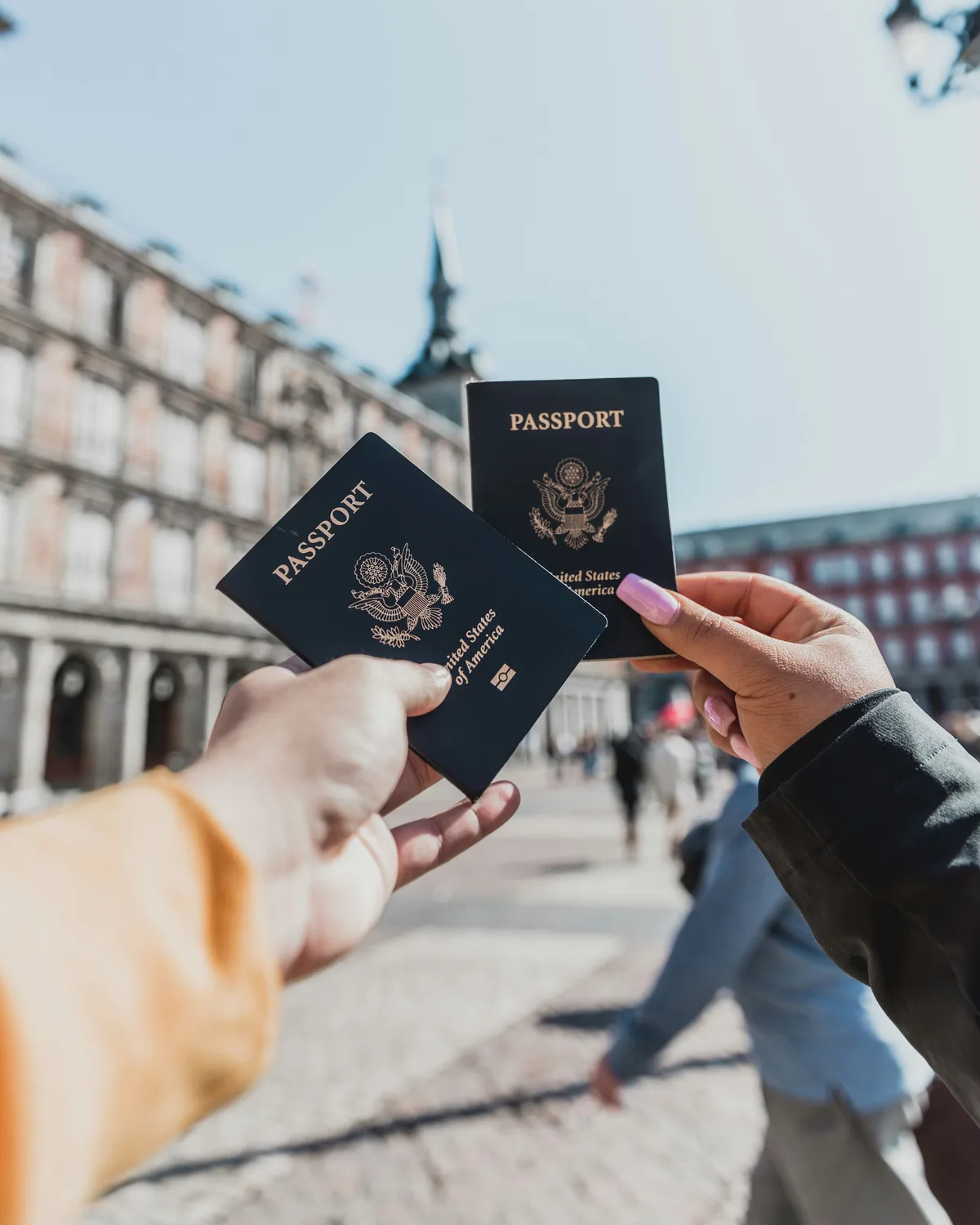 A person holding two passports in one hand