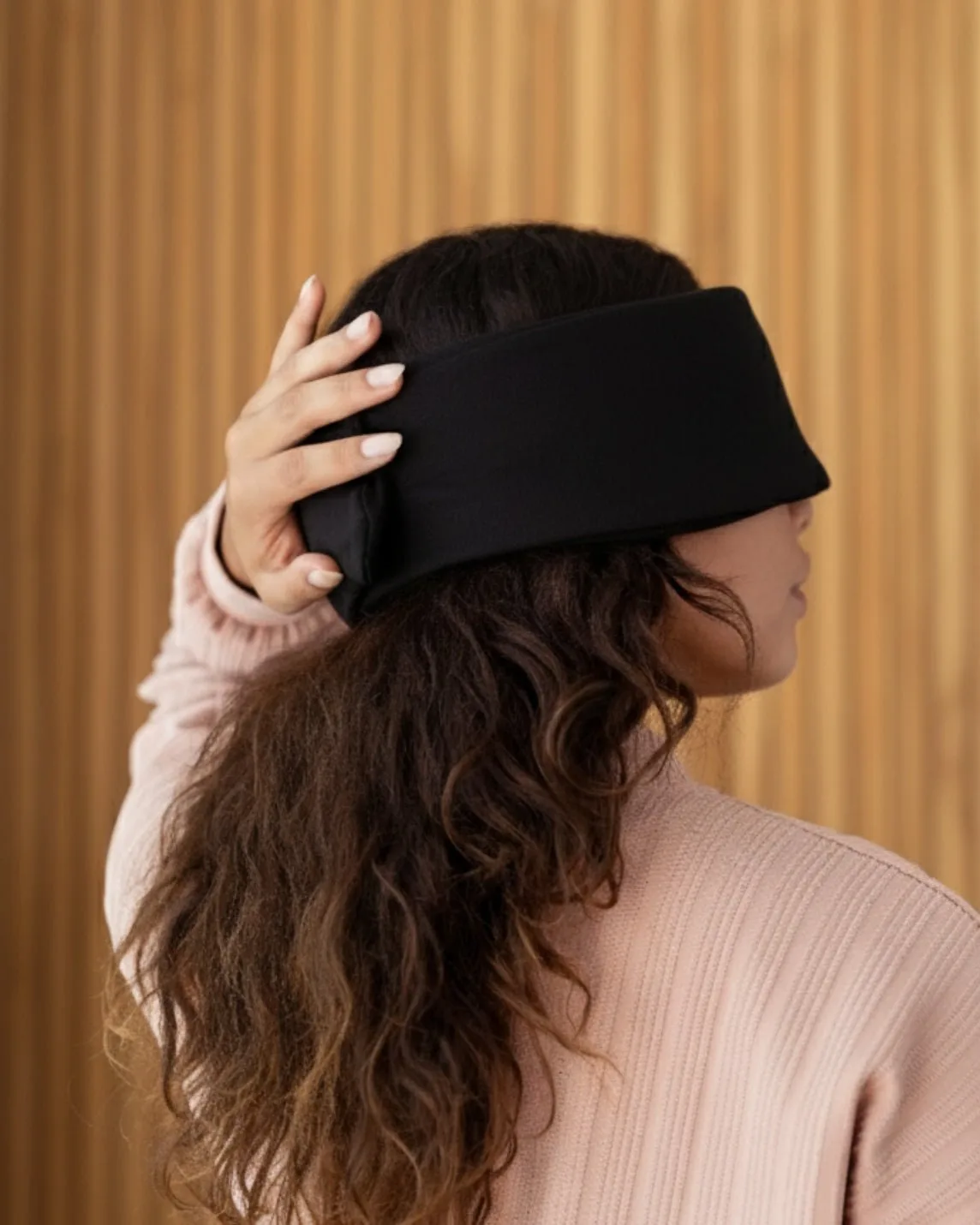A person lying down wearing the black Baloo Living weighted silk sleep mask