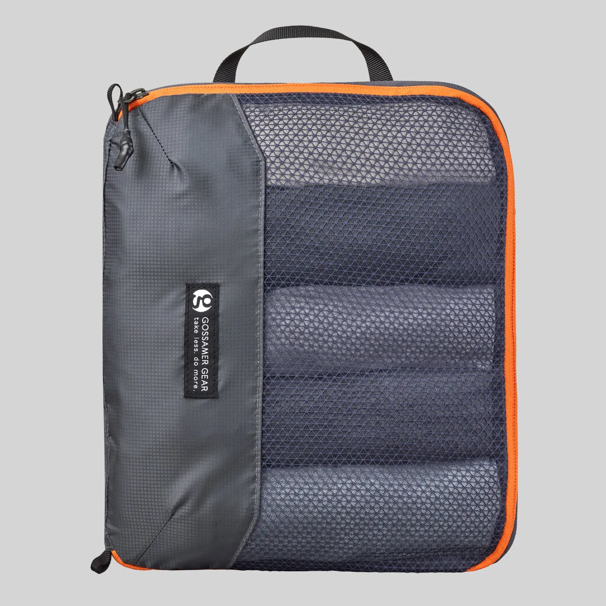 The Gossamer Gear Compression Cube in grey with orange zipper trim and a mesh front panel showing rolled clothing inside