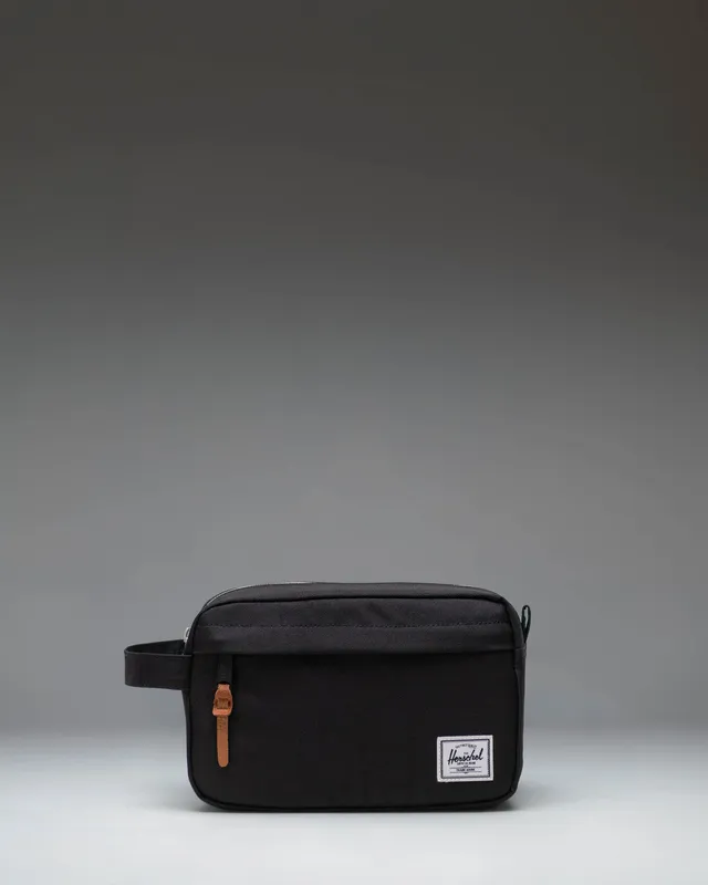 The Herschel Chapter Travel Kit in black, a soft zippered dopp kit with a side grab handle and a signature striped interior lining