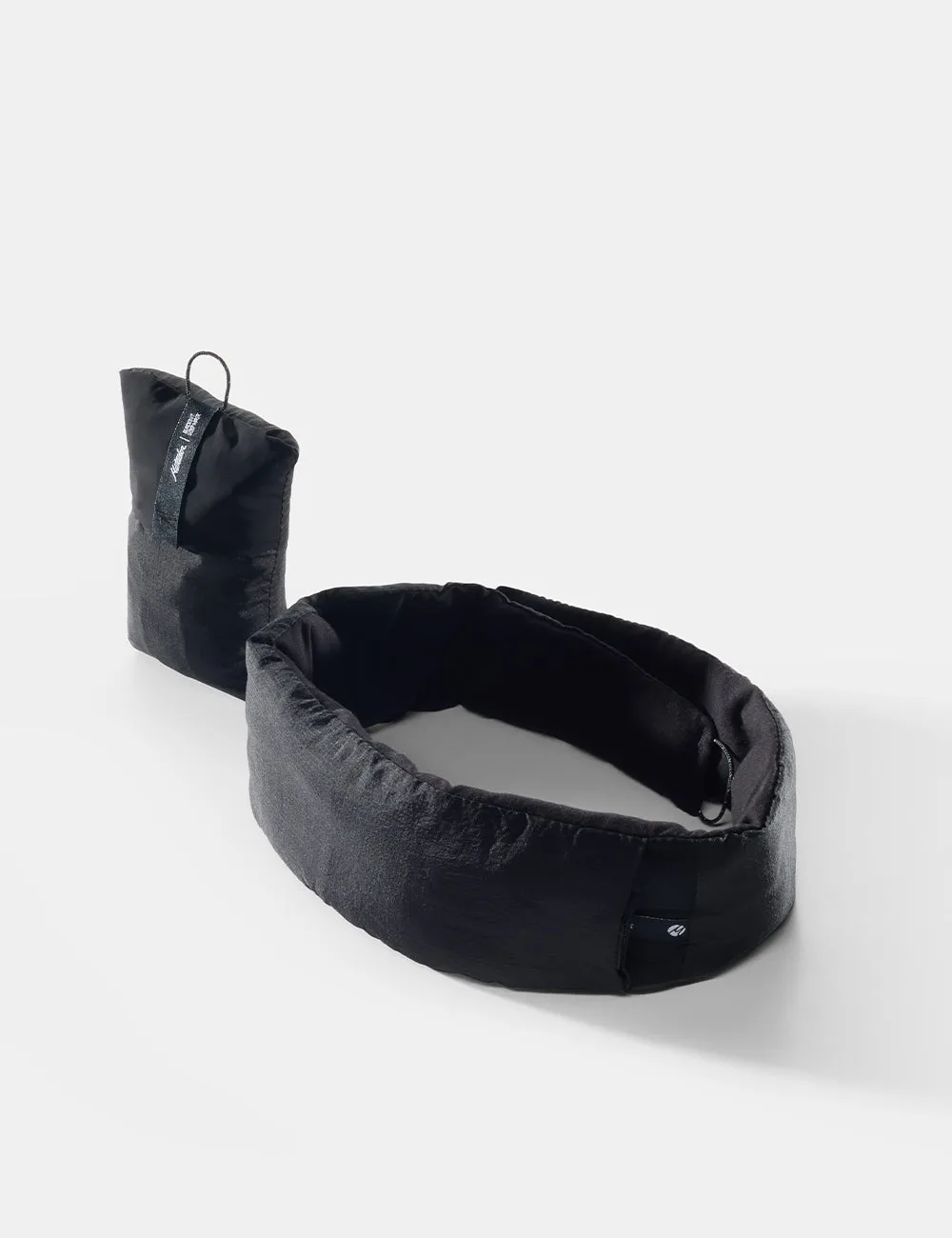 The black Matador Blackout Sleep Mask unrolled beside its small stuff pouch
