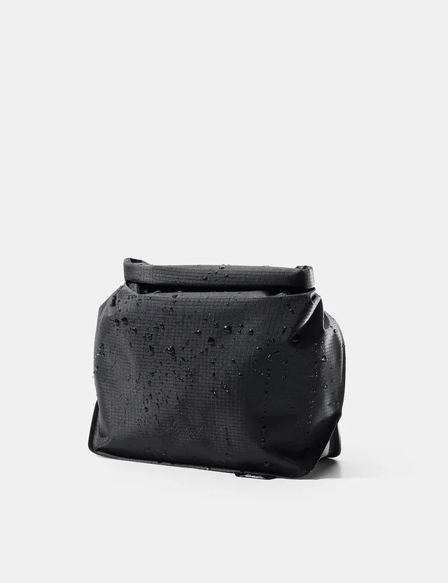 The Matador FlatPak Toiletry Case in black, a flexible ultralight roll-top waterproof pouch with a buckle closure and a hang loop