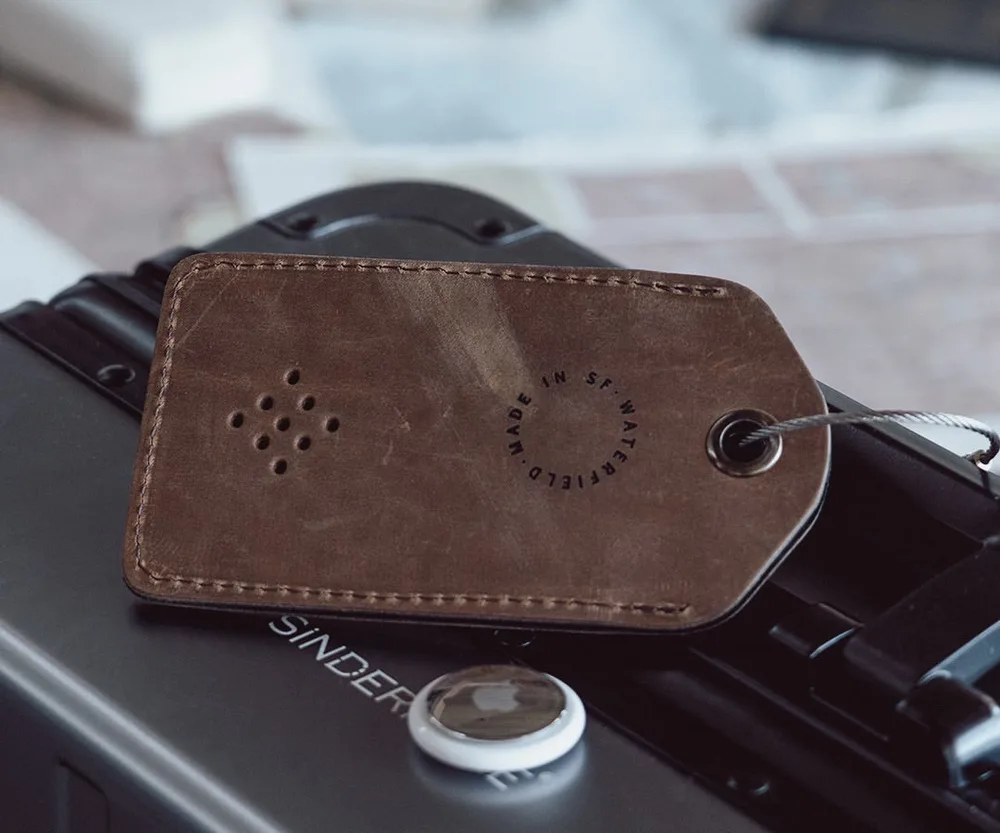 A full-grain leather WaterField luggage tag with a hidden AirTag pocket and steel cable